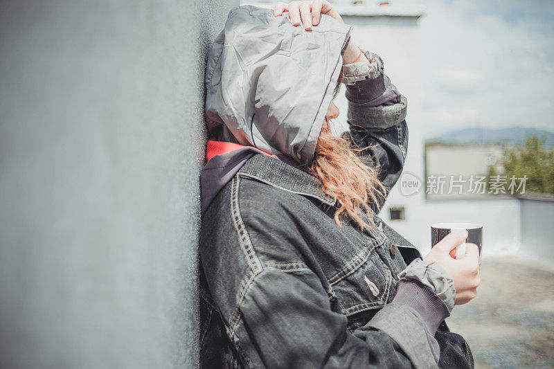 一个美丽的女孩，风的头发在建筑的屋顶享受自由和孤独。