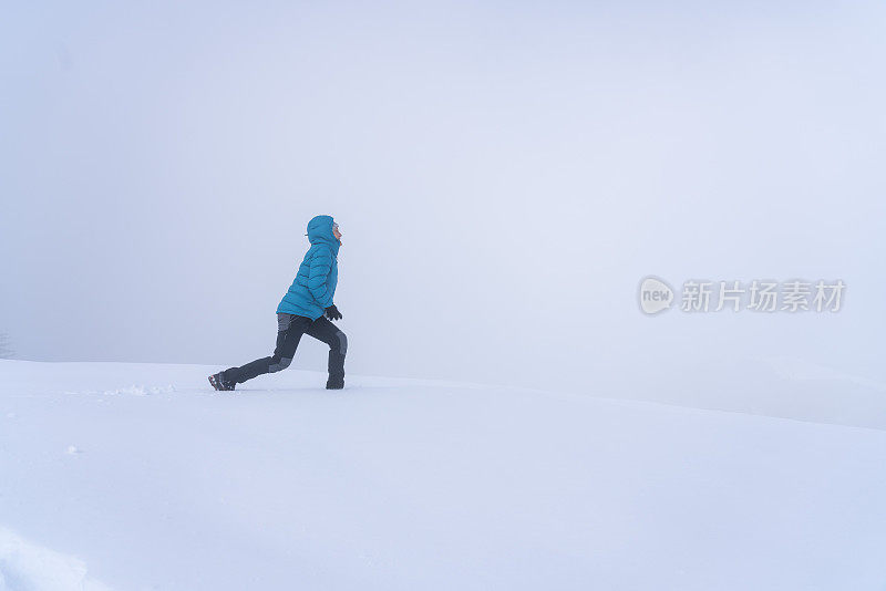 成熟的女人穿着皮大衣在雪和雾中奔跑