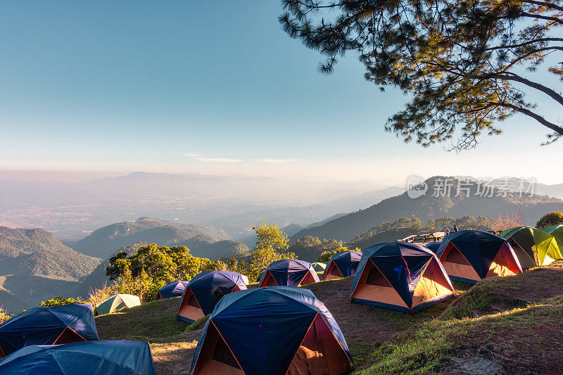 旅游帐篷和露台下的松树森林在日出，野外露营度假冒险户外休闲活动。背包旅游，旅行冒险生活方式