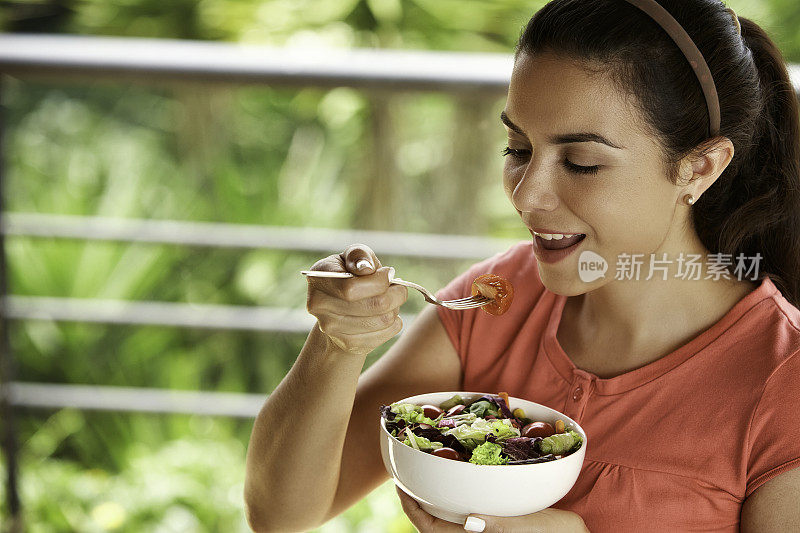 一个西班牙裔可爱的年轻女子午餐吃素食沙拉的特写镜头