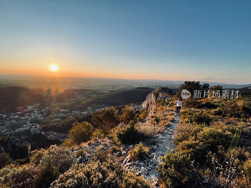 日出时，徒步旅行者沿着阳光明媚的山脊走下去