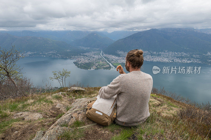 男性徒步者在山顶休息，吃零食