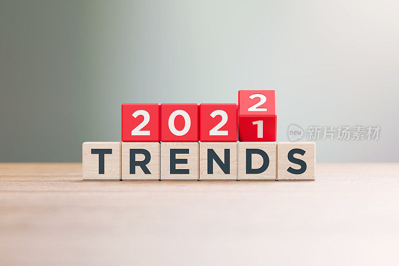 “2021”和“2022趋势”的红色木块坐在离焦背景的木头表面上