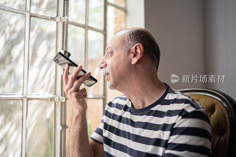 一个在家里用智能手机聊天的成熟男人