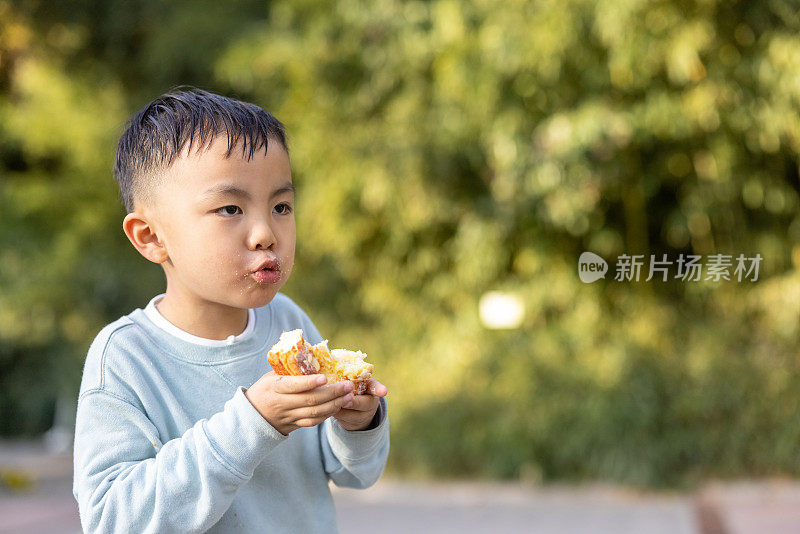 一个男孩正在户外吃面包