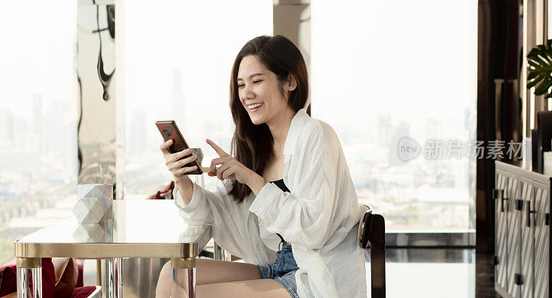 亚洲美女在休闲度假期间，用智能手机轻松、微笑、快乐地在线购物、聊天