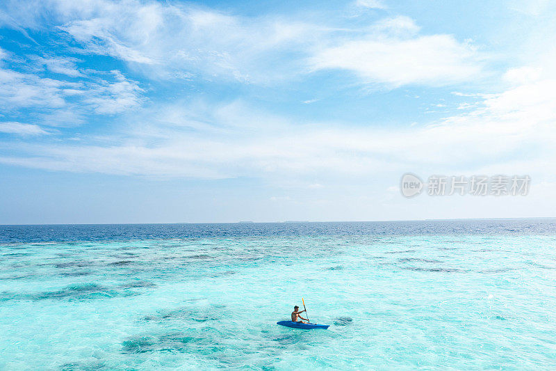 在热带海洋上划着皮艇的年轻人