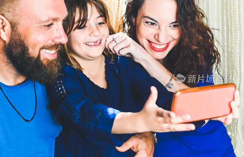 一家人用手机一起自拍或视频，爸爸妈妈和女儿在亲密的亲情时刻