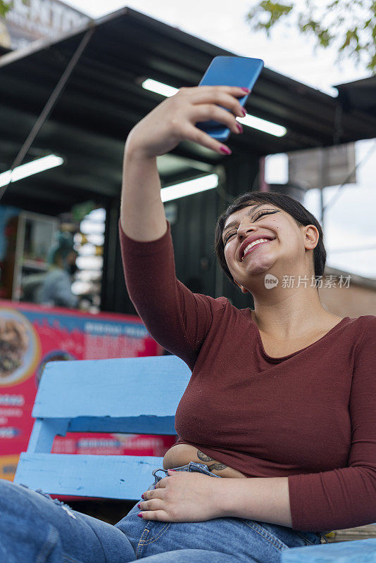 一辆快餐车的拉丁女顾客在等待食物时用手机自拍