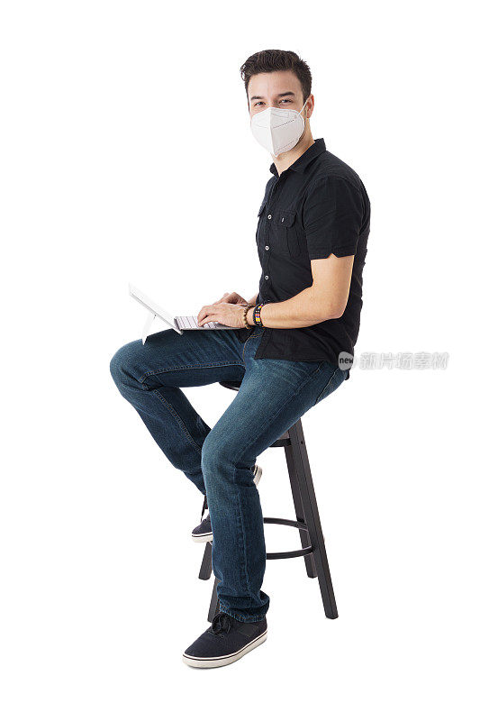 戴口罩的男生坐在笔记本电脑前看着摄像头