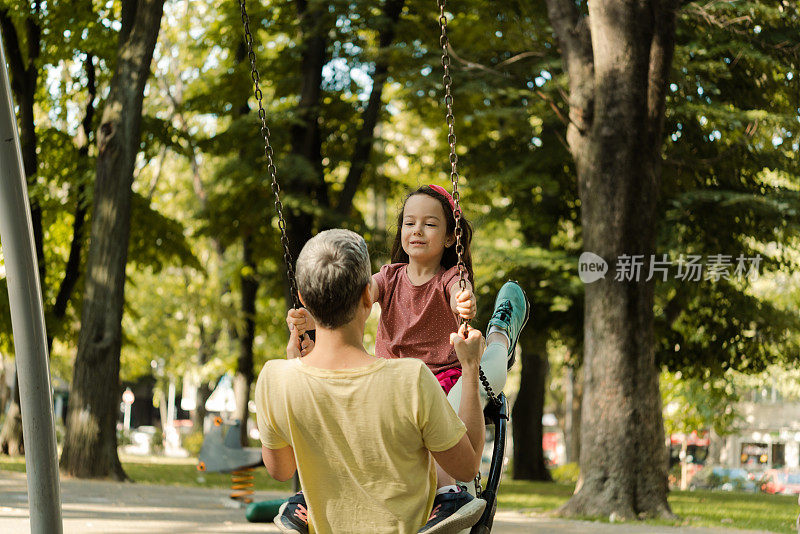 女孩和她妈妈在公园里荡秋千，玩得很开心