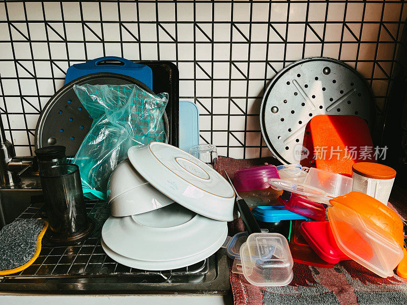 厨房柜台上堆放着干净的盘子和保鲜盒