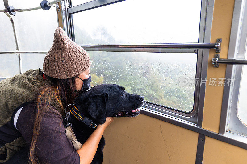 宠物狗和主人一起从山上的索道窗口欣赏风景