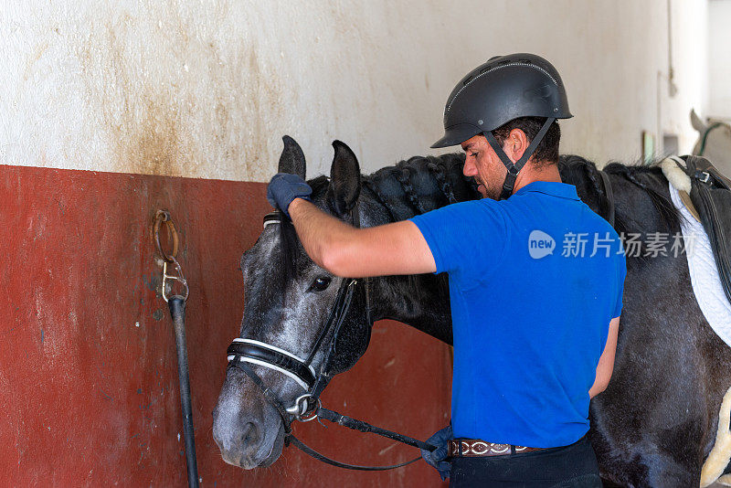 年轻的骑师正准备训练他的马。