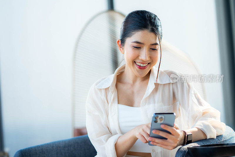 快乐的女人在智能手机上检查社交网络，年轻的女人在家在线聊天，周末在家。