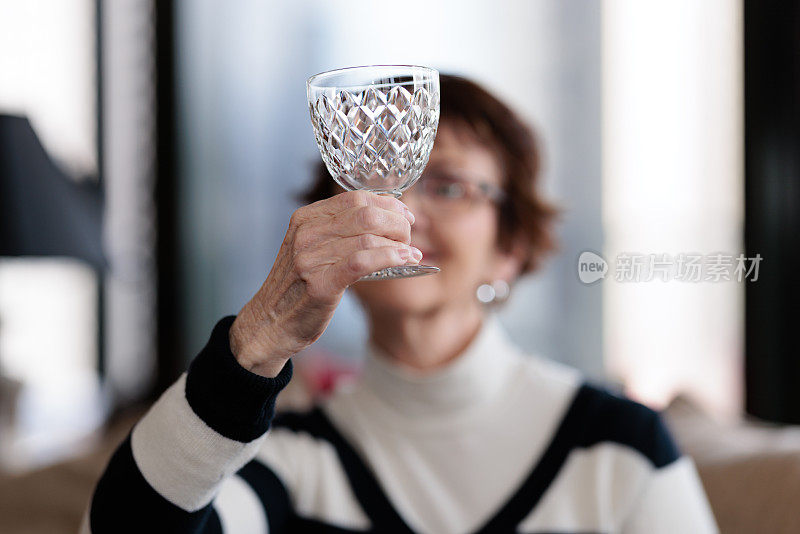 一名女子拿着酒杯对着灯光检查酒杯的状况