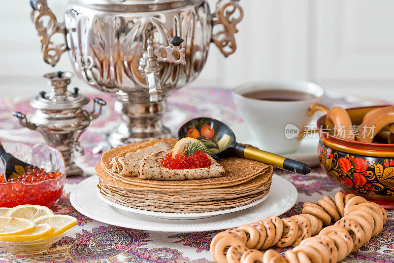 俄罗斯的传统。俄罗斯节日Maslenitsa。静物生活，一杯茶，一堆煎饼，红色鱼子酱，柠檬，百吉饼，棒棒糖公鸡，木勺(khokhloma)和茶炊。