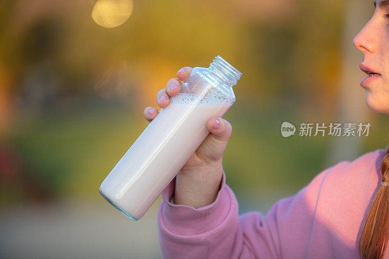 日落时分，一名年轻女子在公园慢跑时补水。