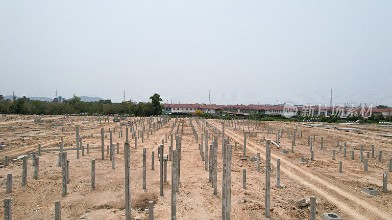 许多灰色的垂直钢筋混凝土柱在一个工业设施的施工现场，蓝天为背景，基础设施新建