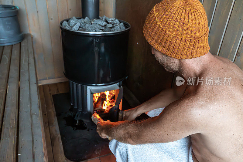 一个年轻人在一个漂浮的桑拿浴室里放松，他打开了烧木头的炉子