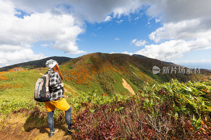 一位女性徒步旅行者停下来欣赏秋天的山景