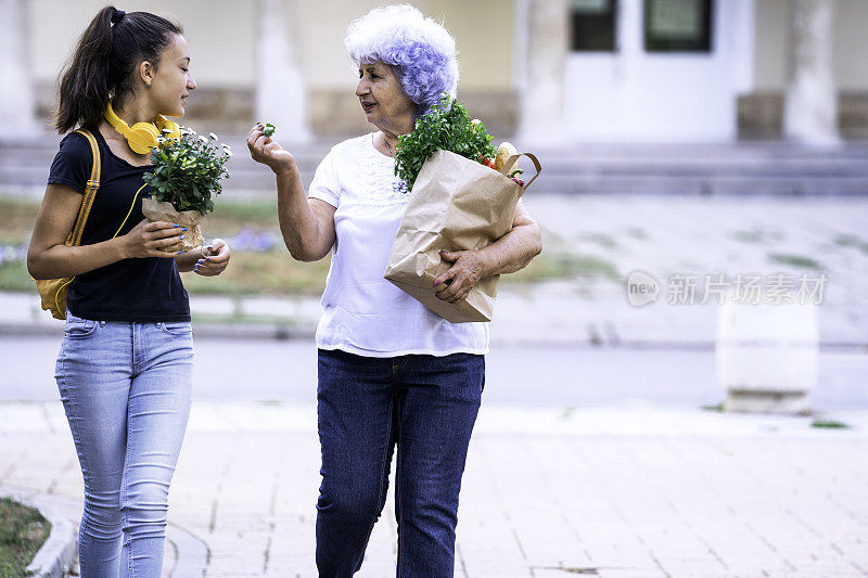 祖母和孙女提着购物袋。老人拿着杂货。