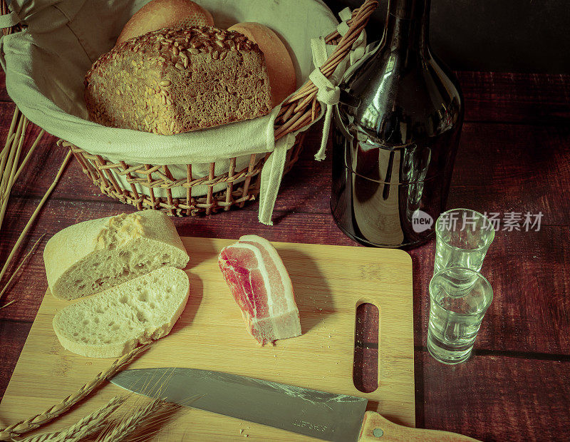 古风质朴的静物画配上面包、麦穗、火腿和培根。