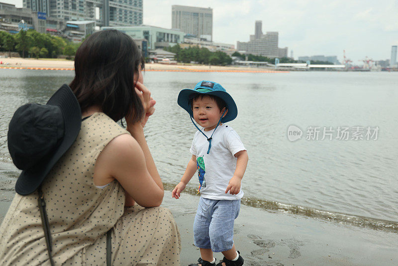 年轻的母亲和她的小儿子在海滩上玩耍