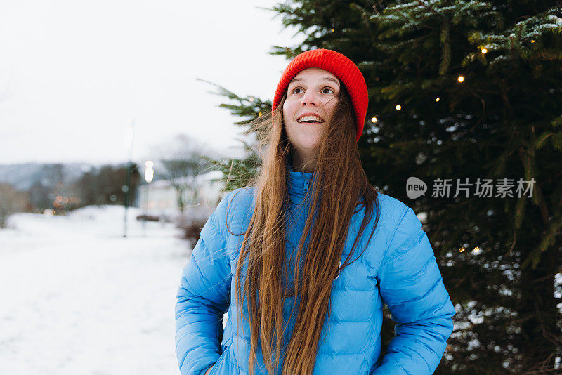 在挪威的城市里，戴着红帽的快乐女人在思考圣诞节的冬天