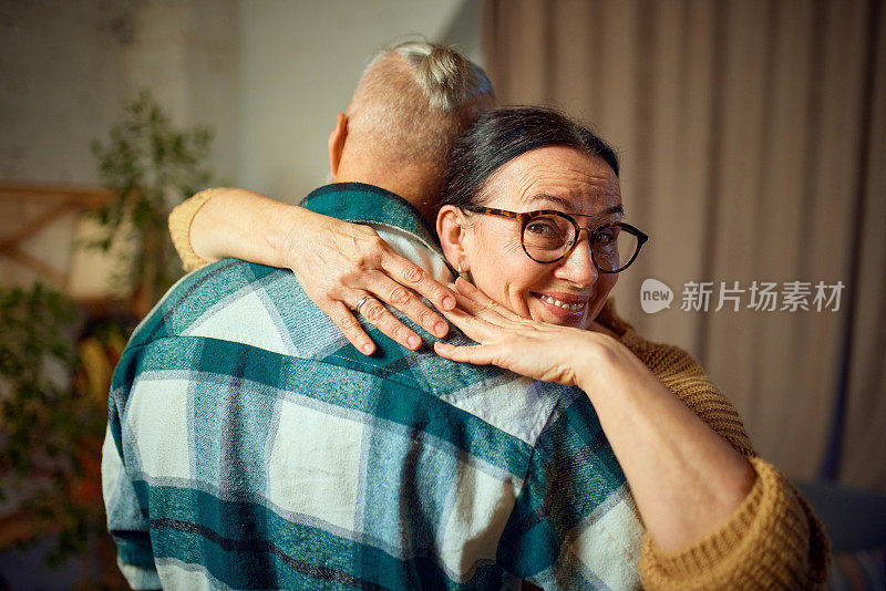 老年人的爱情。老夫妇在家里舒舒服服地过着幸福的退休生活。高级女子，妻子拥抱她的男人，丈夫在家里的客厅里跳舞。