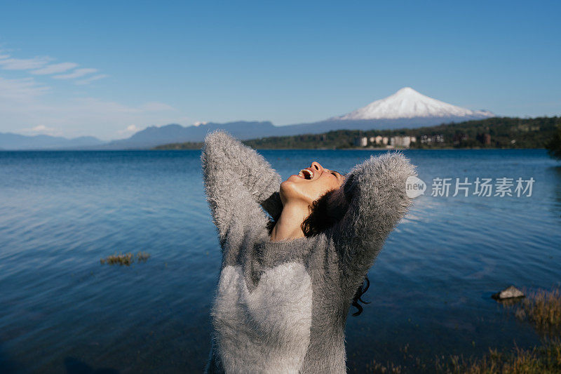 一名女子在湖边做着大喊大叫的手势