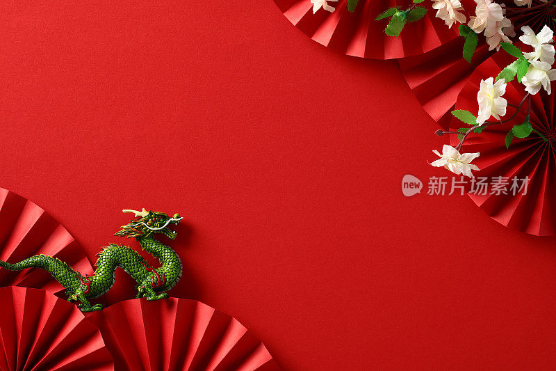 农历新年背景。中国龙，折扇，红底樱花。平躺，俯视图。