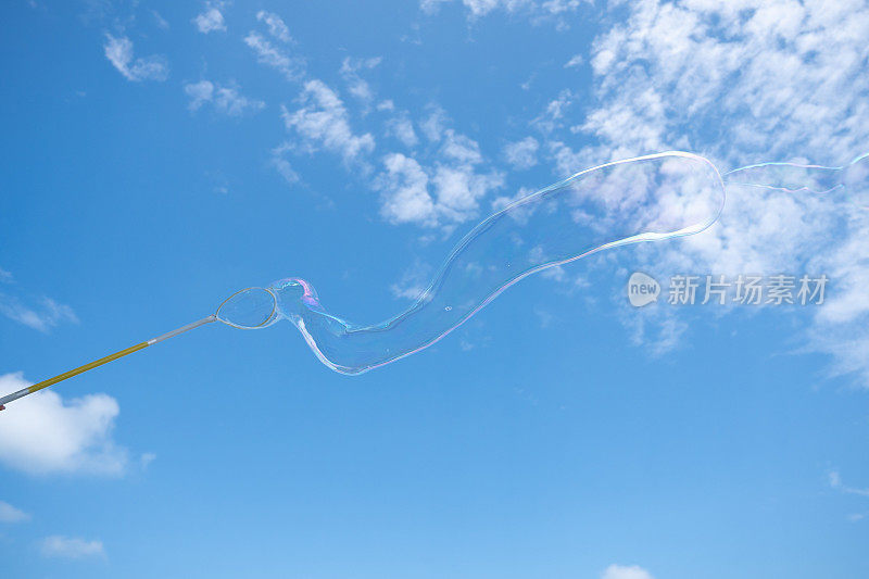 巨大的肥皂泡毫不费力地漂浮在充满活力的蓝天上