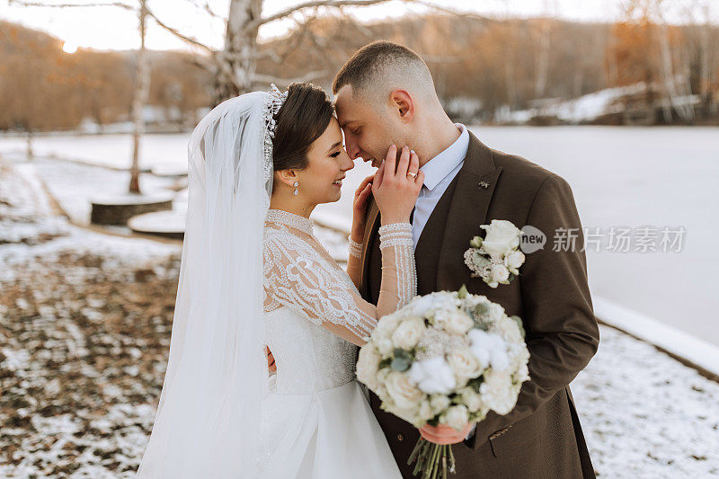 新娘和新郎的结婚照。冬天在大自然中漫步。新娘和新郎拥抱亲吻。精致的衣服