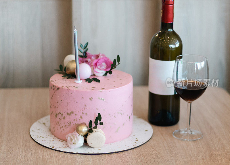粉红色的蛋糕，一瓶酒和一个杯子在桌子上。