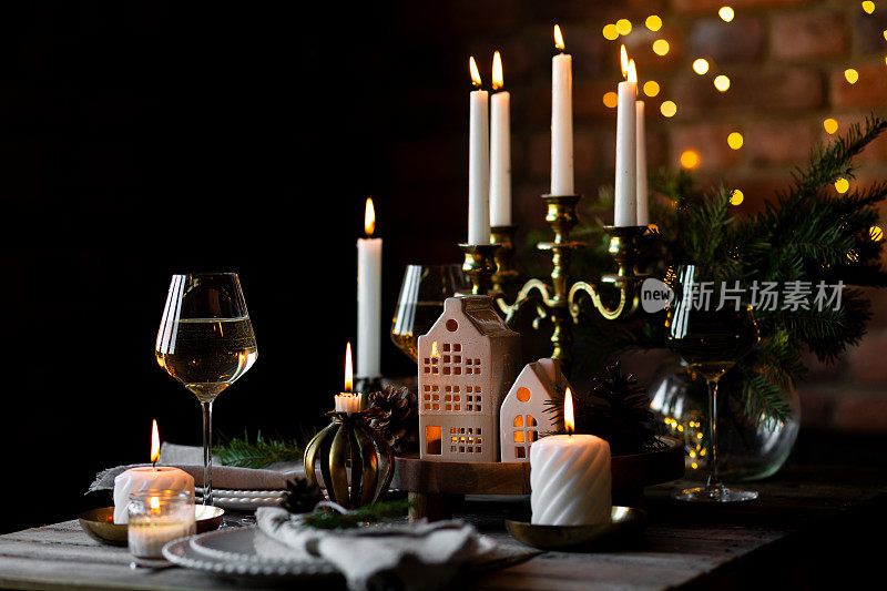 圣诞家庭晚餐的优雅装饰。中间有燃烧的蜡烛，复古的枝形吊灯。零浪费环保可重复使用的家居装饰，杉木树枝。温馨的氛围，木制家具