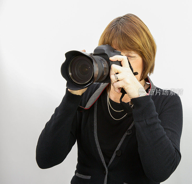 一名女性摄影师正在用数码单反相机拍照