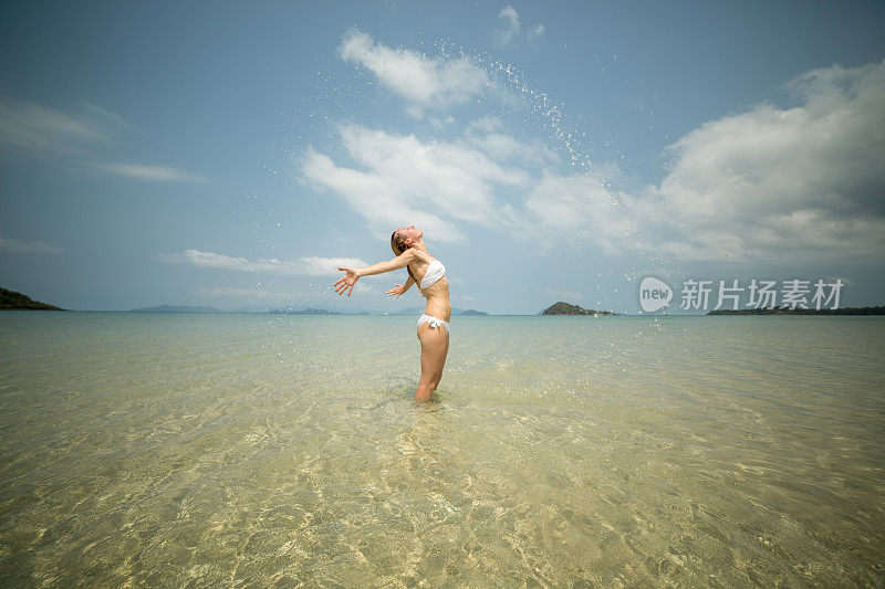 女人在海滩上用头发在海里溅水