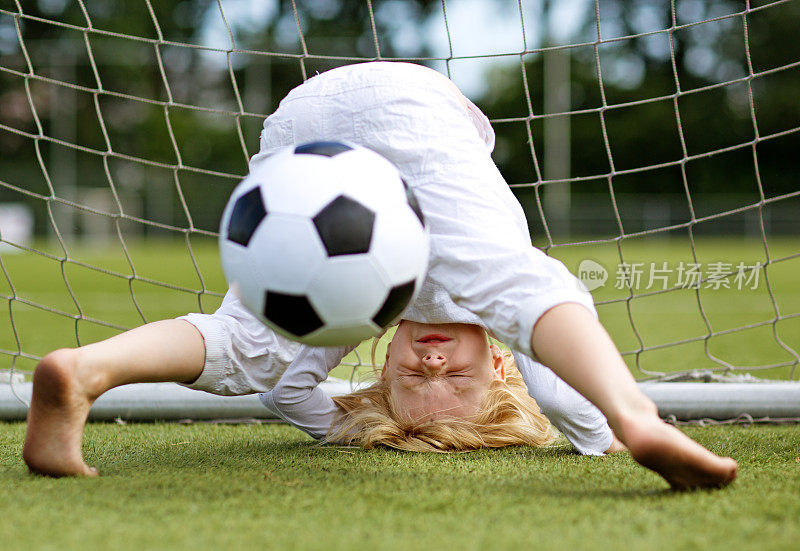 年轻的金发女孩在踢足球