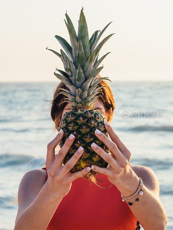 年轻女子在海滩上拿着菠萝