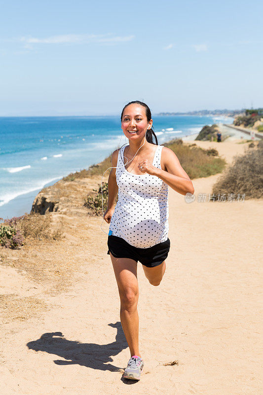 美丽的孕妇沿着海岸慢跑以保持健康