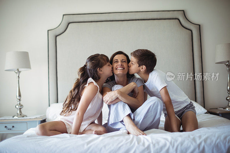 孩子们在卧室里亲吻妈妈的脸颊