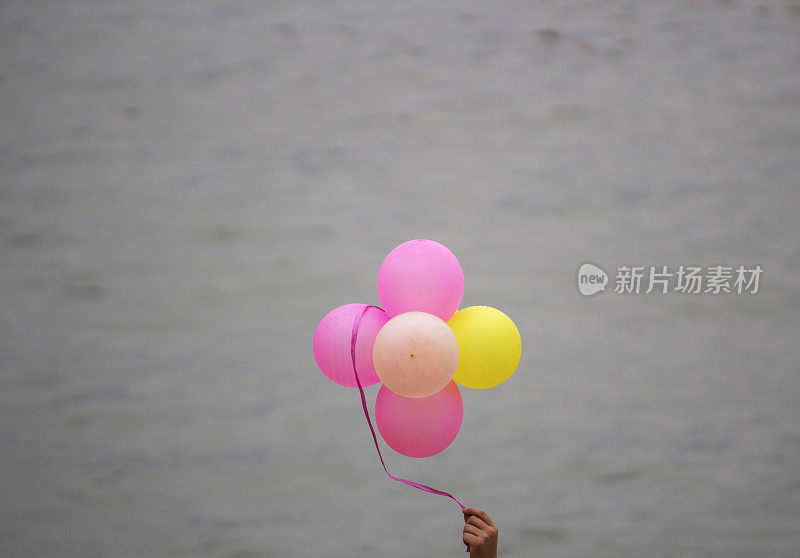 手捧彩色气球在海边