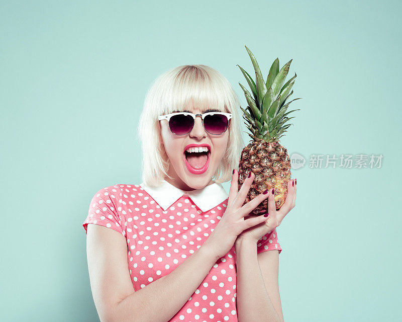 兴奋的金发年轻女子拿着菠萝