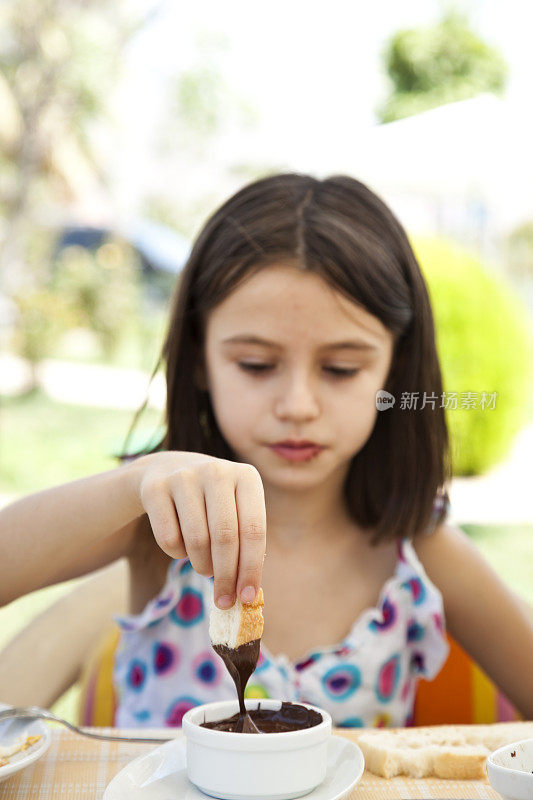 可爱的女孩伸手去拿花生酱，背景是花园