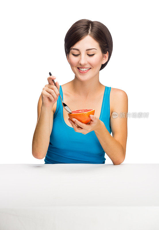 年轻的拉丁女人在吃葡萄柚