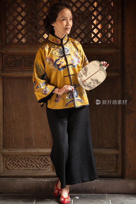 身着传统服饰、手持老式扇子的成熟中国女性