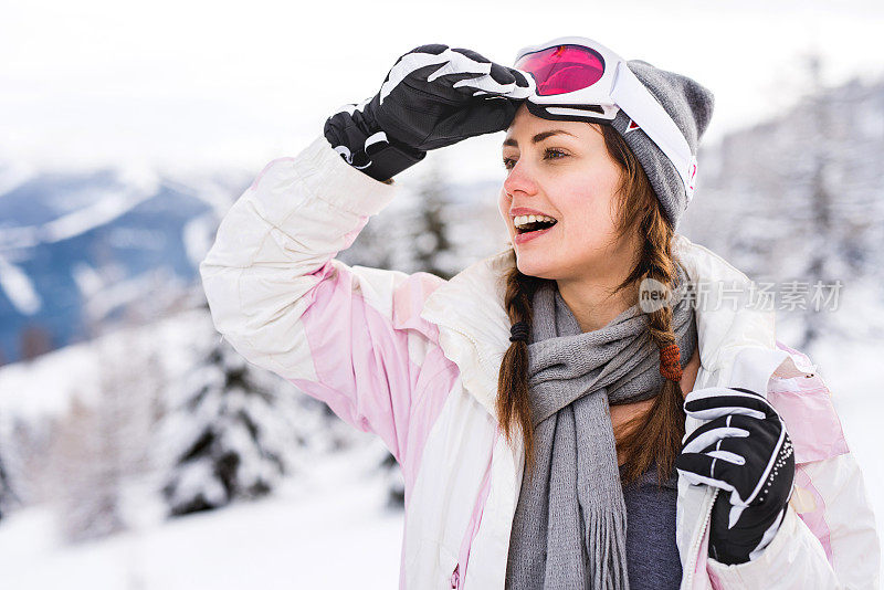 冬天在山上穿滑雪服的快乐女人。