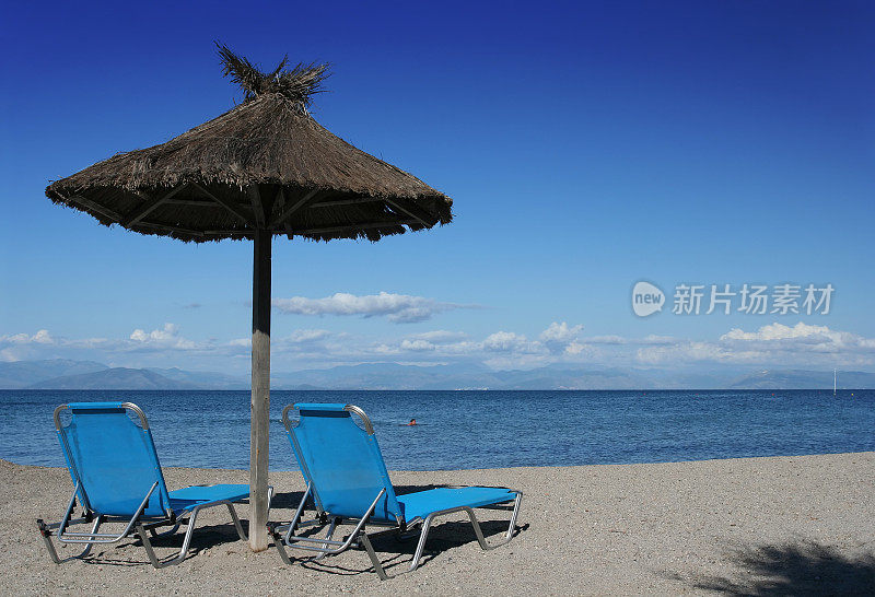 热带海滩上的两把椅子和一把雨伞