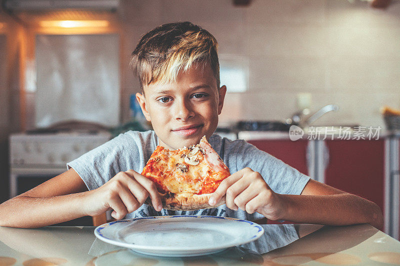 快乐的男孩在家里享用披萨